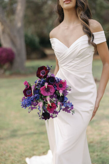 Closeup of a bride holding a dark purple and blue bouquet