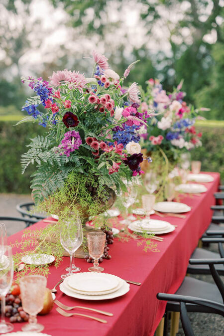 Reception table decorated with floral urns in the garden of Parker Ranch